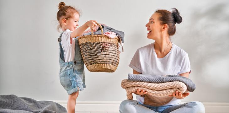 Niña mostrando el cesto de ropa sucia a su madre