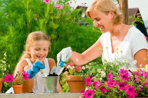 Una mujer con su hija plantando flores en el jardín