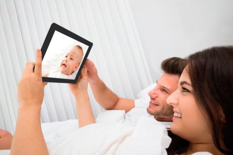 Una pareja contempla a su bebé a través de una tablet