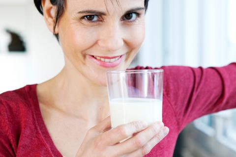 Una mujer sostiene un vaso con leche de soja