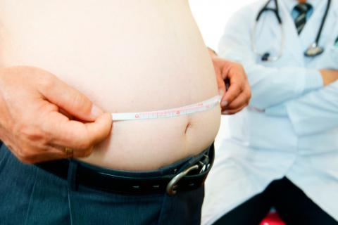 Hombre con sobrepeso se mide el perímetro abdominal en presencia de su médico