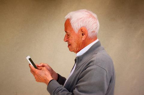 Hombre mayor consulta una aplicación en su móvil