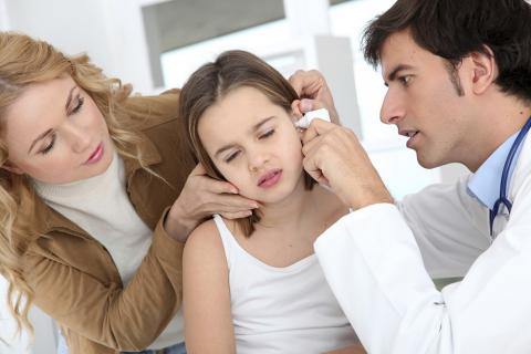 Un médico examina el oído de una niña
