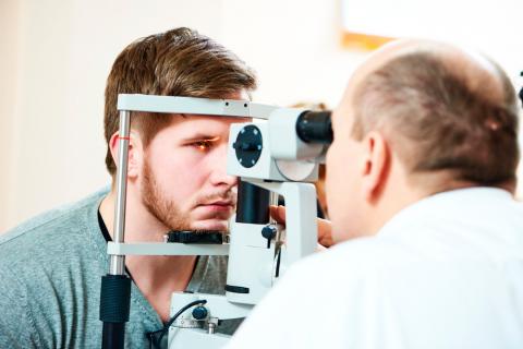Un oftalmólogo revisa el fondo de ojo a un paciente