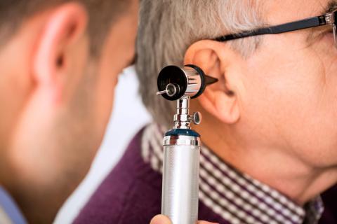 Un otorrino examina el oído a un paciente mayor