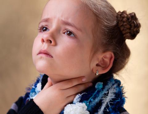 Una niña se toca la garganta con gesto de dolor