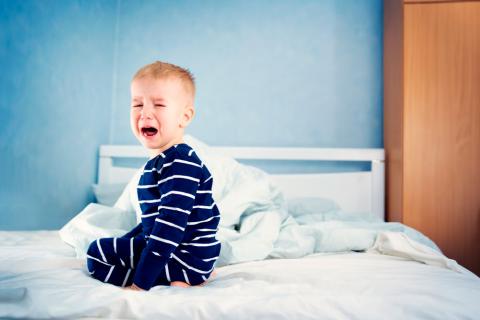 Niño con miedo llorando en la cama