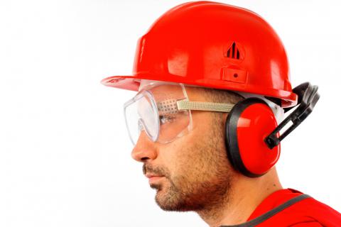 Un obrero con casco y gafas y auriculares protectores