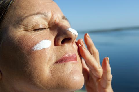 Una mujer se aplica crema bronceadora en la cara