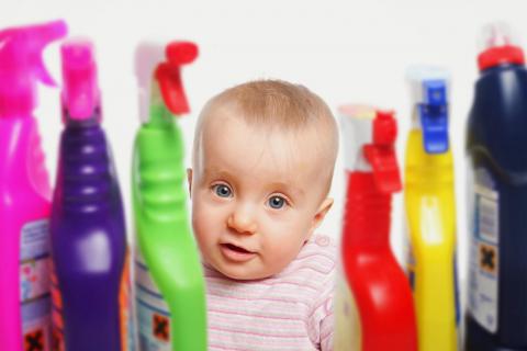 Bebé rodeado de envases de productos de limpieza