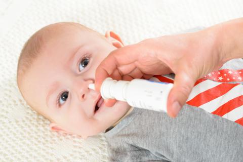 Un padre aplica suero fisiológico en la nariz de su bebé