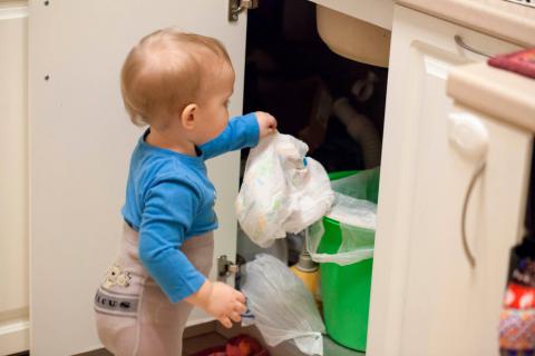 Un niño pequeño a punto de tirar un pañal sucio al cubo de basura