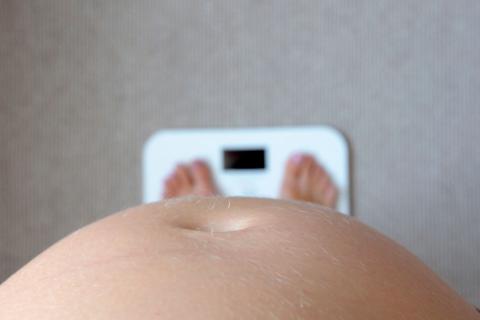 Mujer embarazada pesándose con síntomas de pregorexia