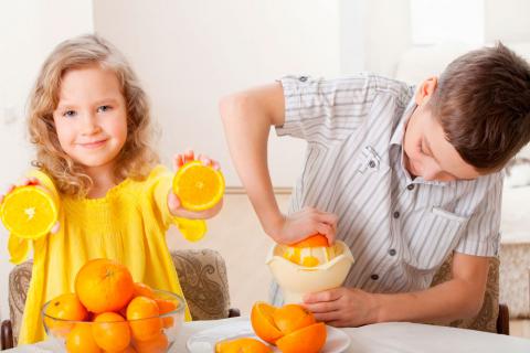 Niños exprimiendo naranjas para hacerse un zumo