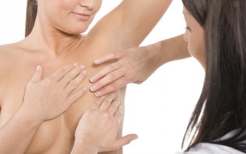 Una profesional sanitaria explora axilas y mamas a una paciente