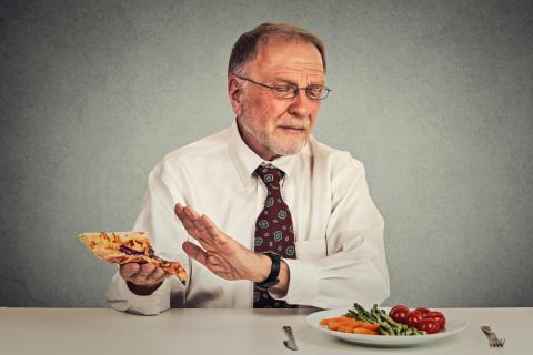 Un hombre con dispepsia rechaza un alimento indigesto para tomar unas verduras a la plancha