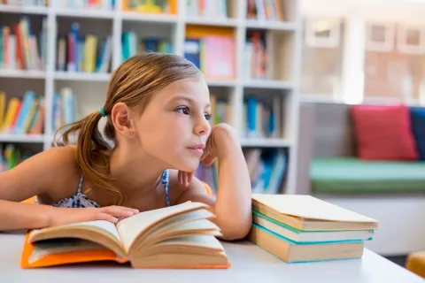 Una niña pensativa apoya la mano en la mejilla mientras estudia