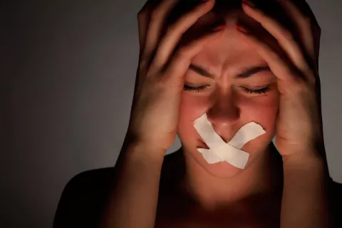 Mujer con esparadrapos cubriéndole la boca y gesto desesperado