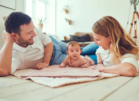 Cómo prevenir el síndrome del bebé retenido Padres con su bebé en una manta para prevenir el síndrome del bebé retenido