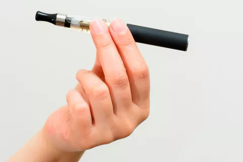 Cigarro electrónico o e-cigarette Persona sujetando un cigarro electrónico con la mano