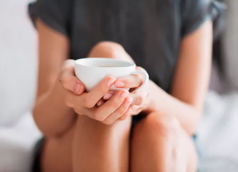 Mujer tomando una infusión de rusco para combatir las varices