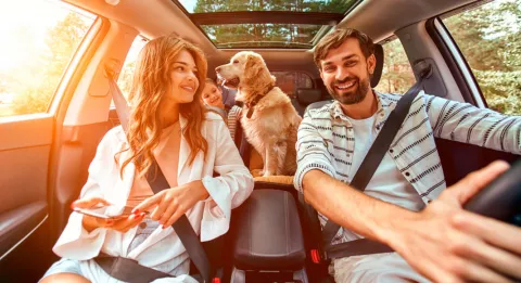 Familia viajando en el coche con su perro