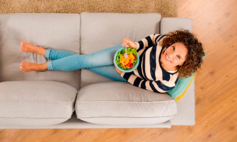 Vista superior de una mujer en el sofá comiendo dieta antiinflamatoria