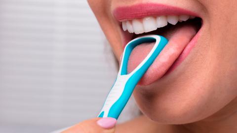 Mujer limpiando su lengua con un rascador