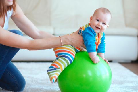 Bebé sentado sobre una pelota de goma