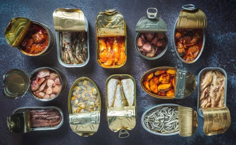 Latas de conservas de pescados abiertas, ¿saludables? Diversas latas de conservas de pescados abiertas sobre una tabla de pizarra