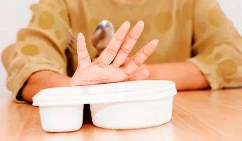 Mano de una señora de tercera edad apartando su comida