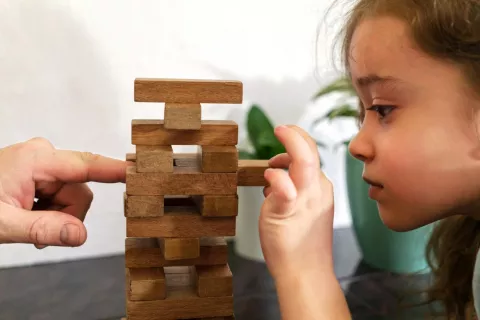 Niña juega con su padre a la jenga quitando una pieza de madera