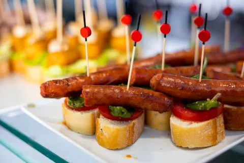 Pintxos de chistorra navarra Chistorra dispuesta en pinchos con pan y tomate sobre una bandeja