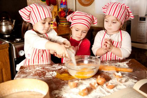 Niños preparan la masa de un pastel en la cocina