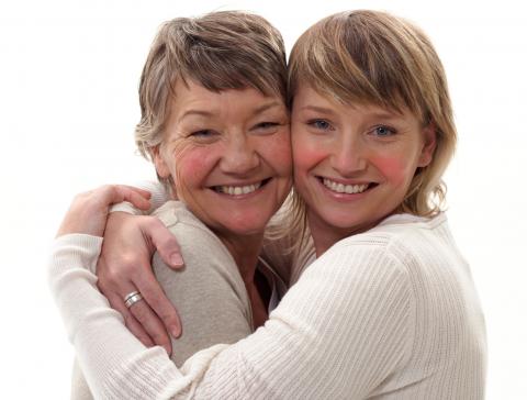 Madre e hija, ambas con rosácea, se abrazan sonriendo a la cámara