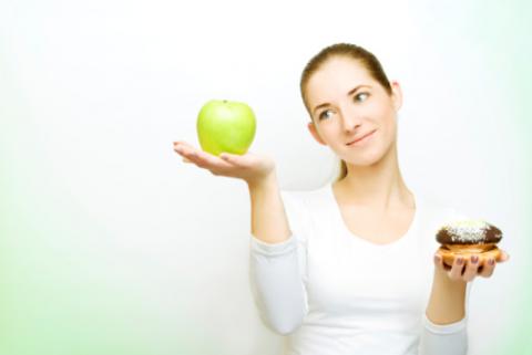 Mujer haciendo una balanza con una manzana y un dulce