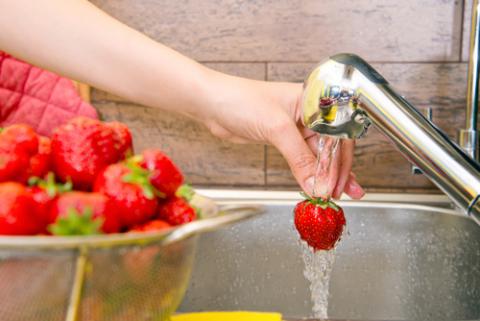 Una mujer lava higiénicamente unas fresas para preparar un plato