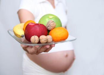 Embarazada con frutas y vitaminas