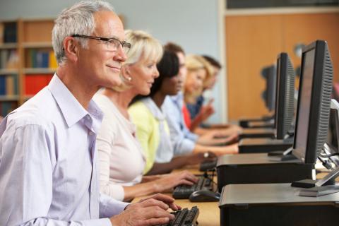 Grupo de personas de mediana edad en un aula con ordenadores