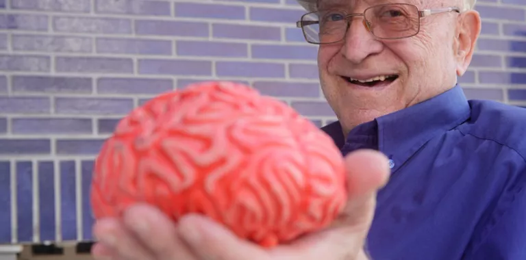 Anciano sujetando un modelo 3D de un cererebro
