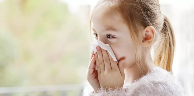 Niña resfriada se suena la nariz con un pañuelo