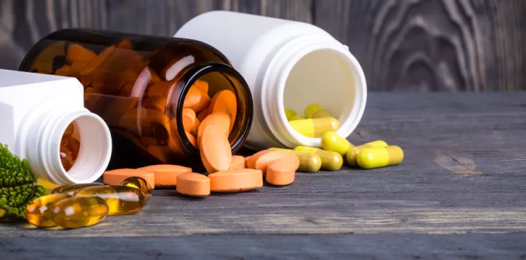 Tres frascos abiertos de los que salen píldoras con suplementos dietéticos