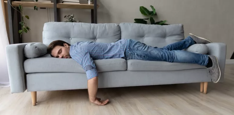 Hombre joven tumbado en el sofá echándo la siesta