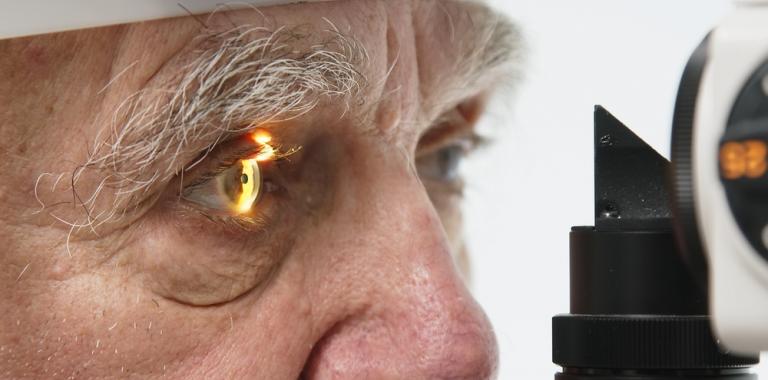 Un oftalmólogo examina la retina a un anciano.