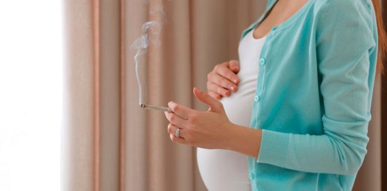 Mujer embarazada con un cigarrillo encendido en la mano