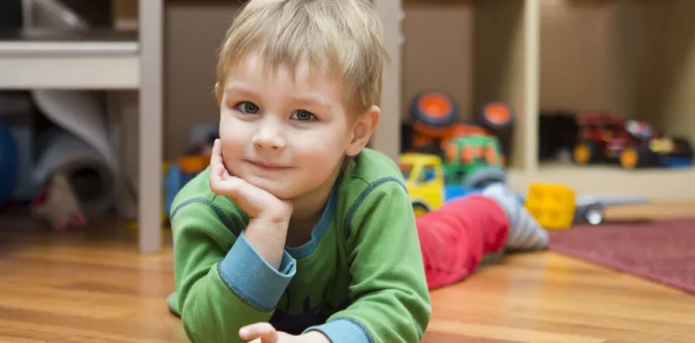 Niño pequeño tumbado sobre el suelo del cuarto de juegos