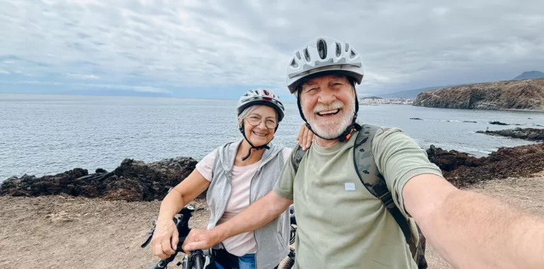 Hombre y mujer mayores se hacen un selfie con sus bicicletas junto al mar