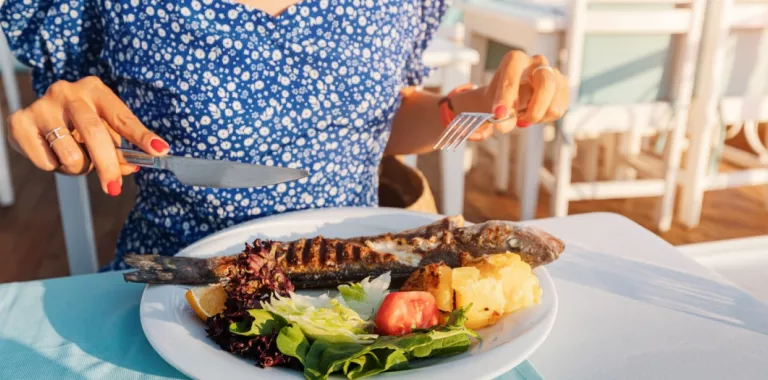 Una mujer se dispone a comer un plato de pescado y verduras