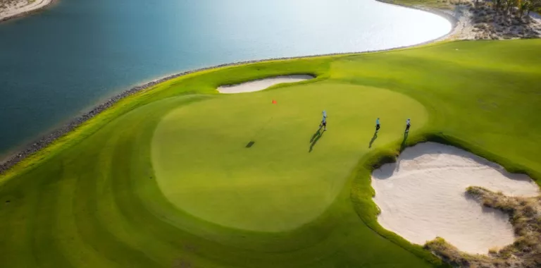 Tres jugadores en campo de golf con una zona con agua