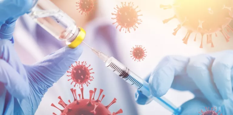 Manos de un sanitario sostienen una jeringa y un vial con vacuna rodeadas por moléculas de virus